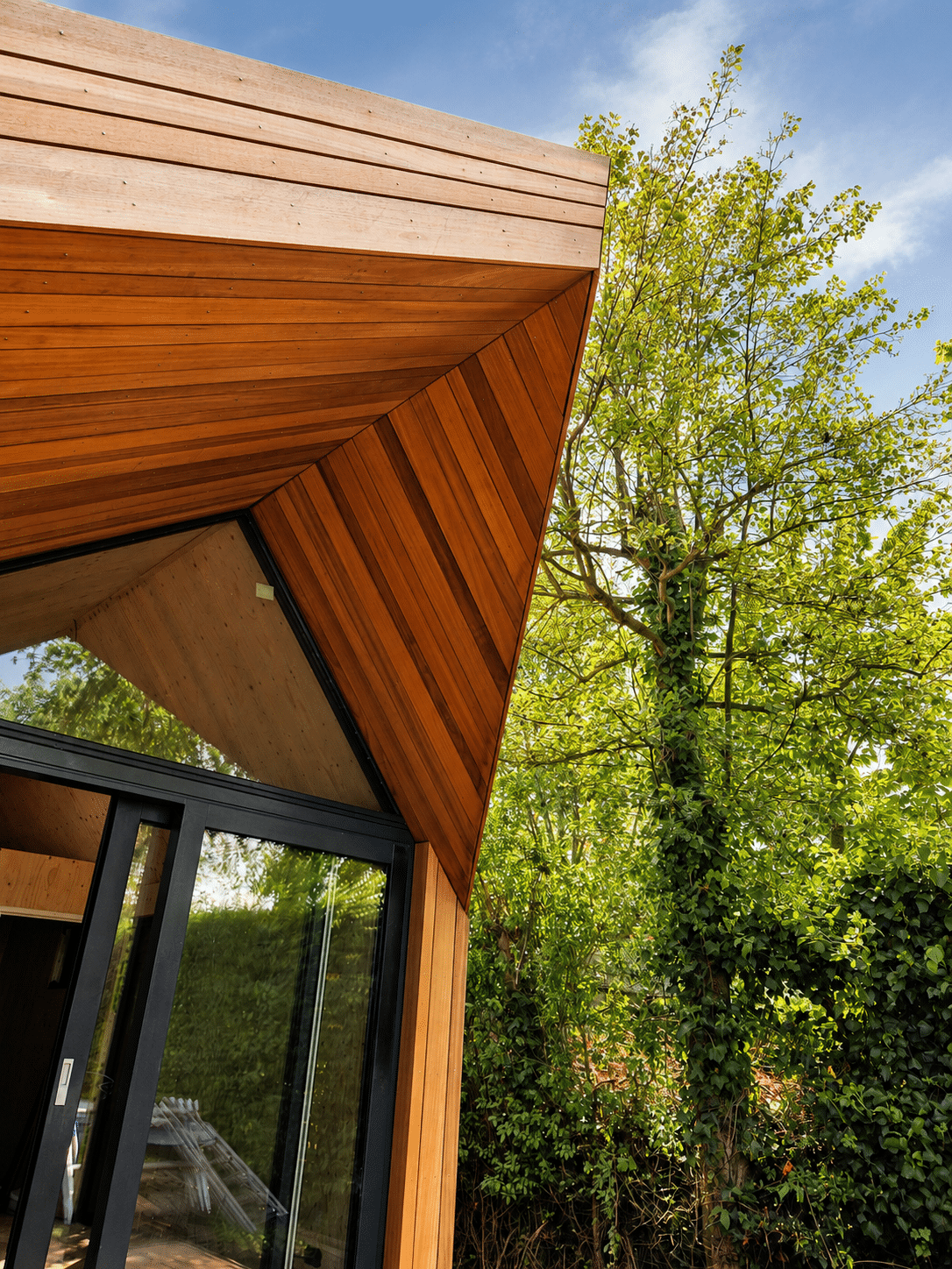 Architektonisches Detail des Holzvordachs mit Thermo Ayous Verkleidung und Glasfront